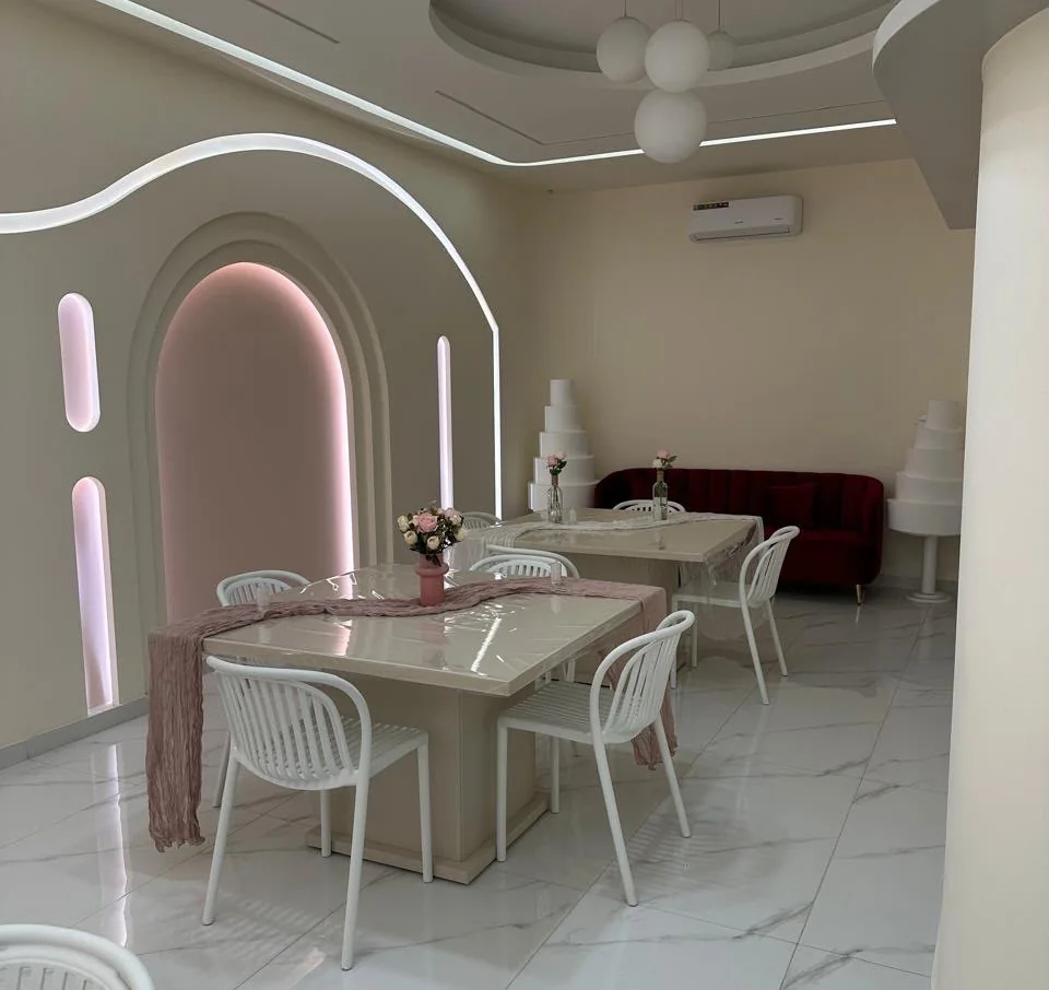The Cakies party space: a pink-lit arch, set tables and a red velvet sofa
